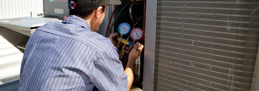HVAC technician servicing a condenser unit in New Iberia