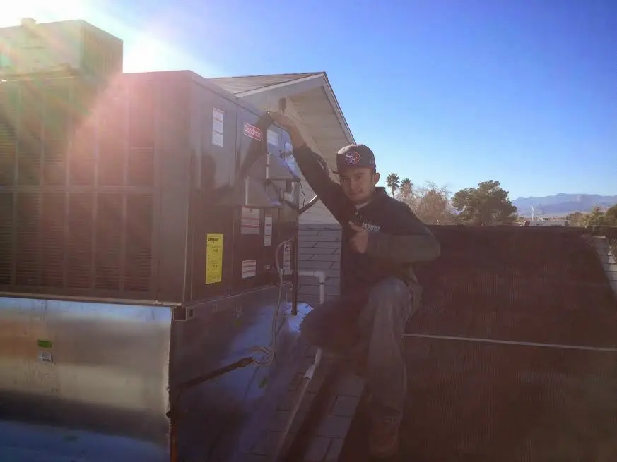 HVAC technician performing AC Tune-Up on a rooftop unit in New Iberia